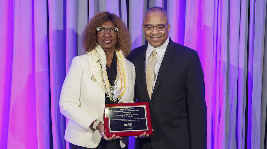 Miriam Mobley Smith receives a plaque from ASHP Board President Paul Walker.