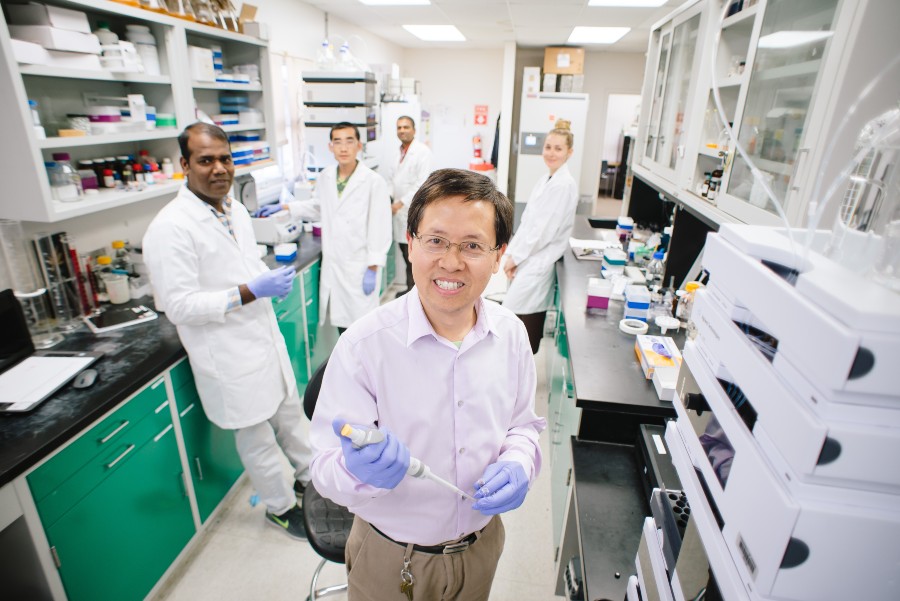 Dr. Shugeng Cao stands in a laboratory with team members behind him